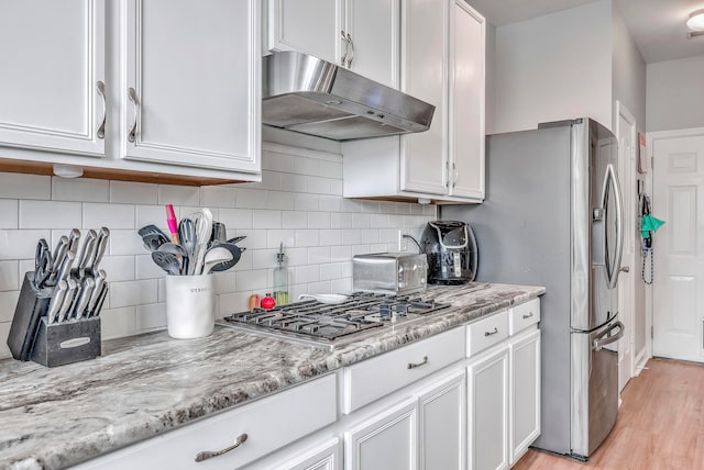 kitchen with stainless steel gas stovetop, light wood-type flooring, white cabinetry, and light stone countertops