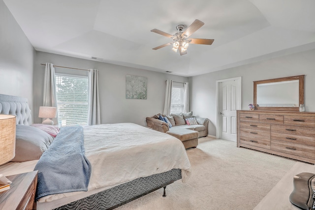 carpeted bedroom featuring ceiling fan and a raised ceiling