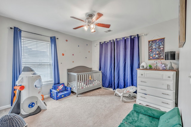 bedroom with carpet floors, ceiling fan, and a nursery area