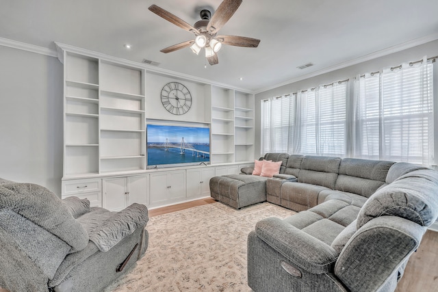 living room featuring light hardwood / wood-style flooring, built in shelves, ceiling fan, and ornamental molding