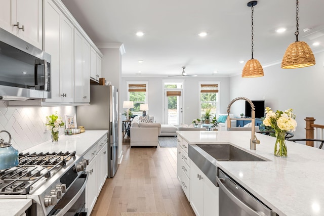 411 Katies Scenic Ct, Wando, SC 29492 - kitchen with stainless steel appliances, a sink, open floor plan, light wood-type flooring, and ornamental molding