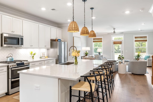 411 Katies Scenic Ct, Wando, SC 29492 - kitchen featuring appliances with stainless steel finishes, a sink, open floor plan, ornamental molding, and light wood-type flooring
