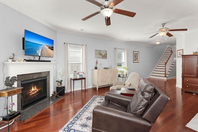 living area featuring stairs, a premium fireplace, wood finished floors, and crown molding