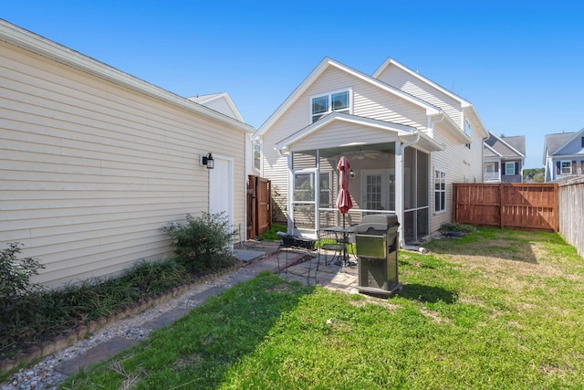 rear view of property featuring a sunroom, a fenced backyard, a yard, a patio area, and a ceiling fan