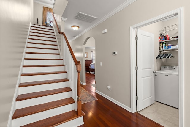 stairway with visible vents, ornamental molding, washer / clothes dryer, hardwood / wood-style floors, and arched walkways