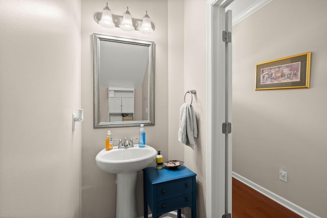 bathroom with a sink, baseboards, and wood finished floors