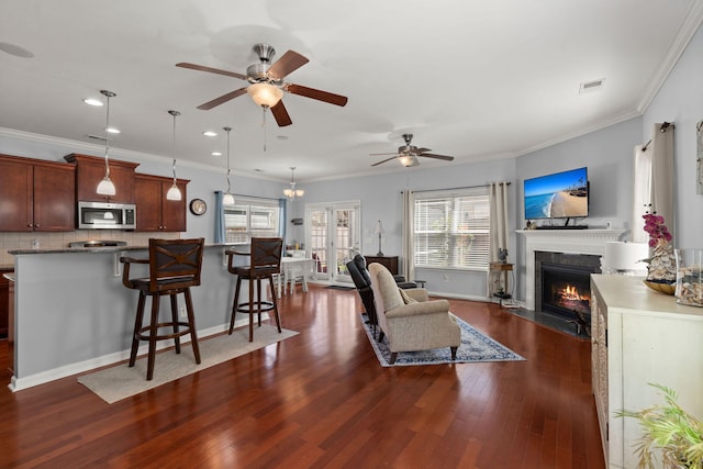 living area with baseboards, a fireplace with flush hearth, dark wood-style floors, and ornamental molding