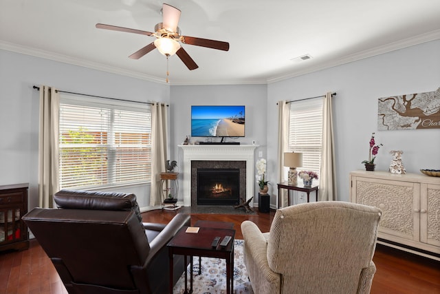 living area featuring ceiling fan, a fireplace with flush hearth, wood finished floors, and ornamental molding