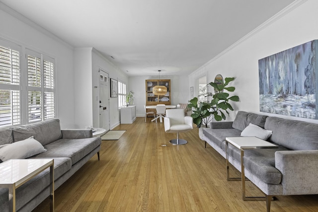 living room featuring baseboards, ornamental molding, and light wood finished floors