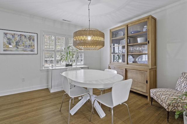 dining area featuring crown molding, wood finished floors, baseboards, and visible vents