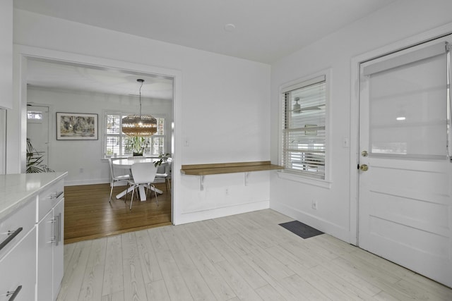 interior space featuring a notable chandelier, baseboards, and light wood-style floors