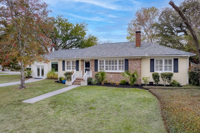 ranch-style home featuring french doors, roof with shingles, a front yard, brick siding, and a chimney