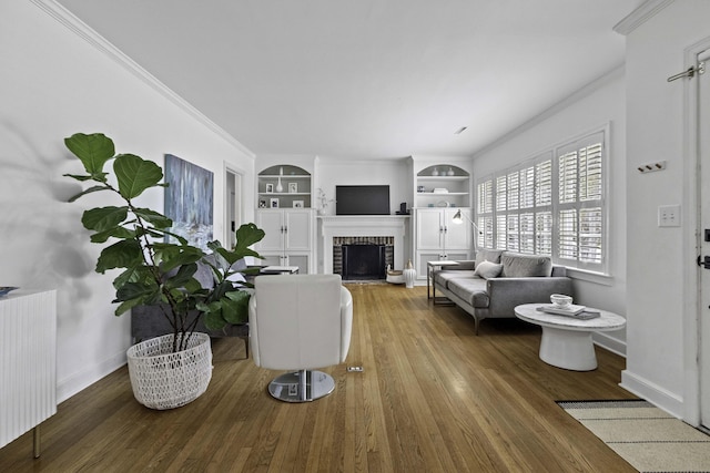 living room with a brick fireplace, built in features, radiator heating unit, ornamental molding, and wood finished floors