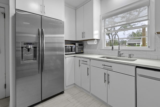 kitchen with a sink, decorative backsplash, appliances with stainless steel finishes, and white cabinetry