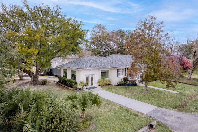 view of front facade featuring french doors, a shingled roof, and a front lawn