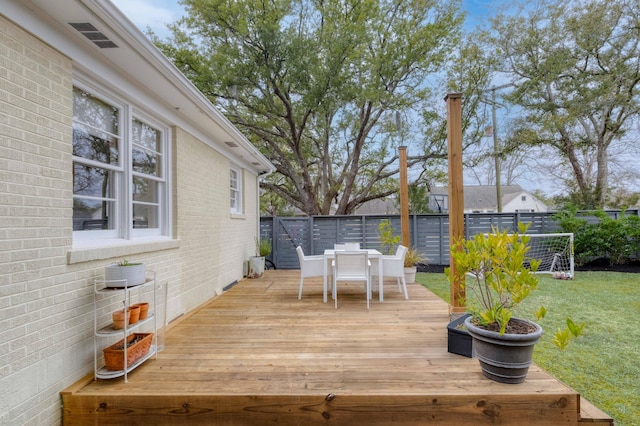 wooden terrace with outdoor dining area, a yard, and fence