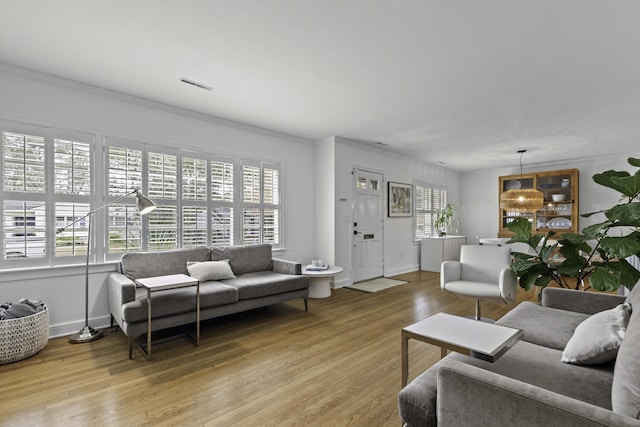 living room featuring a wealth of natural light, visible vents, and light wood finished floors