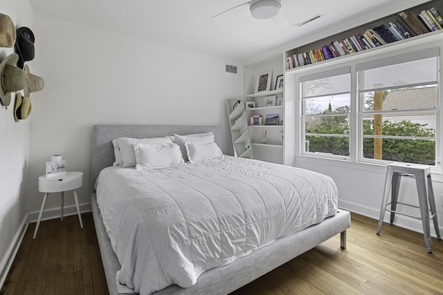 bedroom featuring visible vents, ceiling fan, baseboards, and wood finished floors