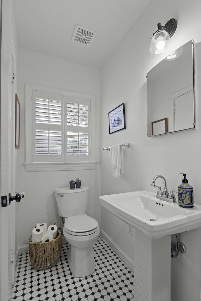 half bath with visible vents, baseboards, and toilet