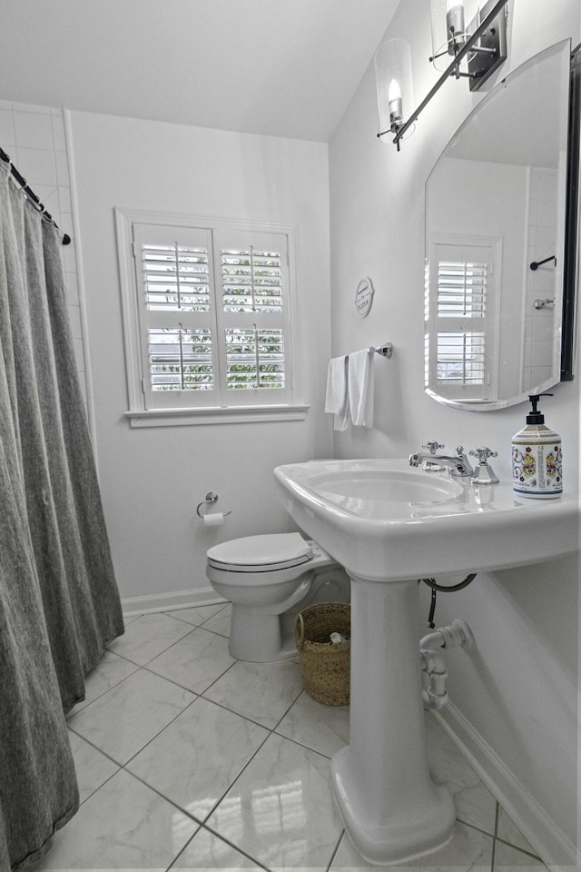 bathroom featuring curtained shower, toilet, and baseboards