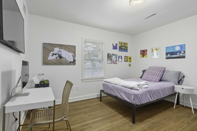 bedroom with visible vents, baseboards, and wood finished floors