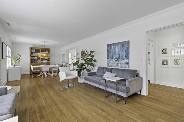 living room featuring visible vents, ornamental molding, baseboards, and hardwood / wood-style floors