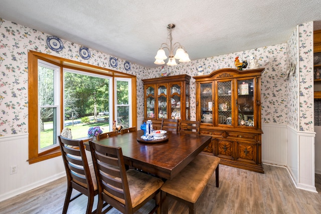 dining space featuring a textured ceiling, a notable chandelier, and light hardwood / wood-style floors