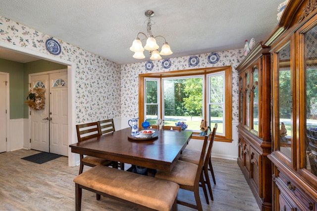 dining area with a textured ceiling, a chandelier, and hardwood / wood-style floors