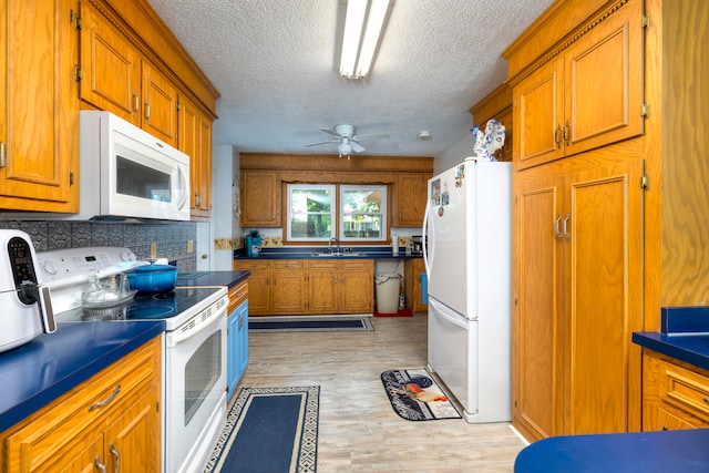 kitchen with white appliances, light hardwood / wood-style flooring, a textured ceiling, sink, and ceiling fan