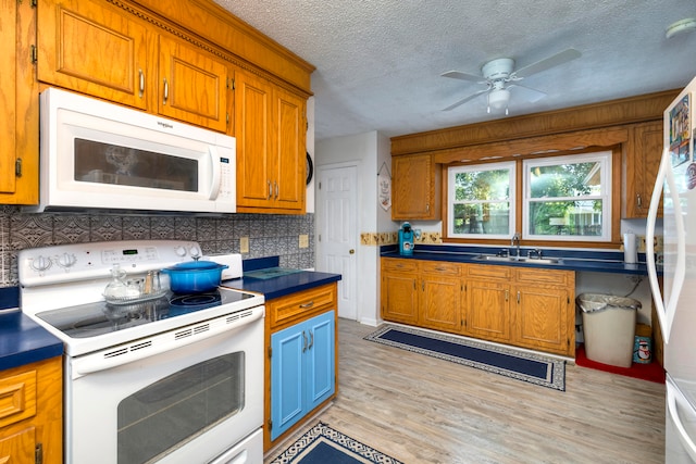 kitchen featuring white appliances, light hardwood / wood-style floors, sink, ceiling fan, and a textured ceiling