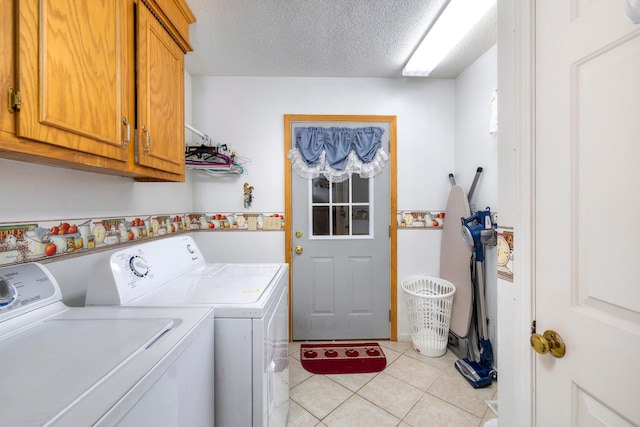 laundry room with light tile patterned floors, a textured ceiling, cabinets, and washer and dryer