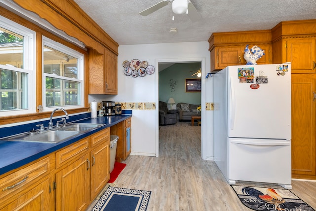 kitchen featuring a textured ceiling, ceiling fan, white fridge, and sink