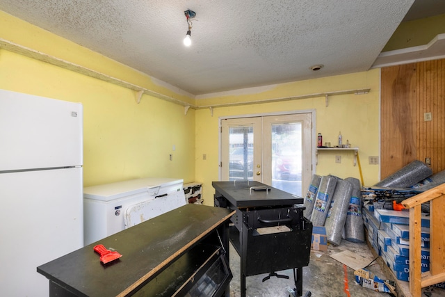 kitchen featuring french doors, a textured ceiling, concrete flooring, and white fridge