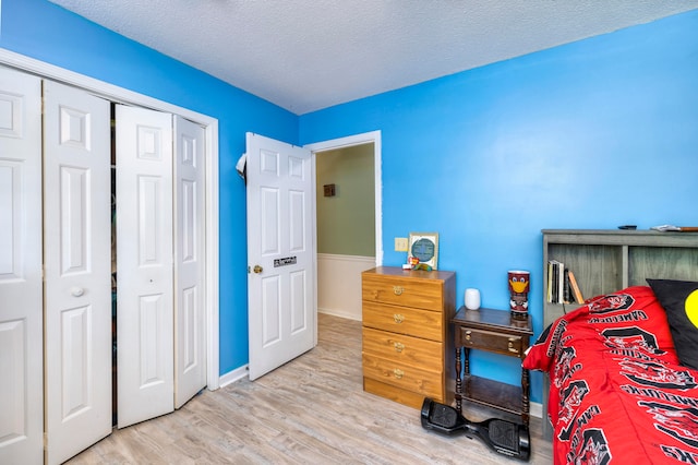 bedroom with light wood-type flooring, a textured ceiling, and a closet