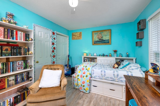 bedroom with a closet, wood-type flooring, ceiling fan, and a textured ceiling