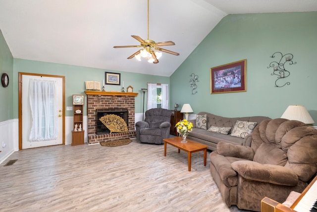 living room featuring a fireplace, ceiling fan, vaulted ceiling, and light hardwood / wood-style floors