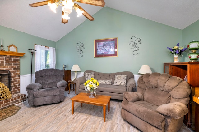 living room featuring ceiling fan, a brick fireplace, vaulted ceiling, and light hardwood / wood-style floors