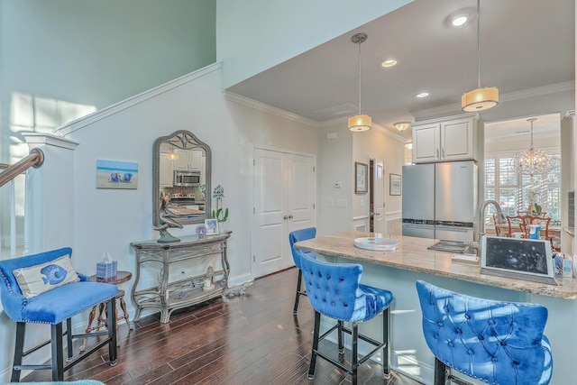 kitchen featuring a breakfast bar area, dark wood-style flooring, ornamental molding, freestanding refrigerator, and light stone countertops