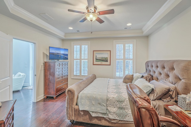 bedroom featuring dark wood-style flooring, a raised ceiling, visible vents, and crown molding