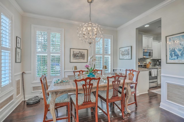 dining room featuring dark wood-style floors, ornamental molding, a wainscoted wall, and a chandelier