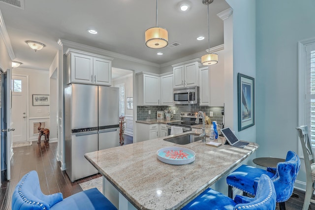 kitchen featuring tasteful backsplash, a peninsula, stainless steel appliances, crown molding, and a sink