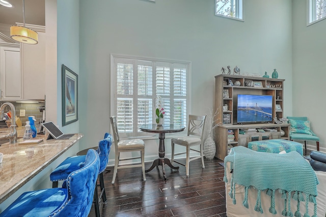 dining room with dark wood-style floors, a towering ceiling, and baseboards