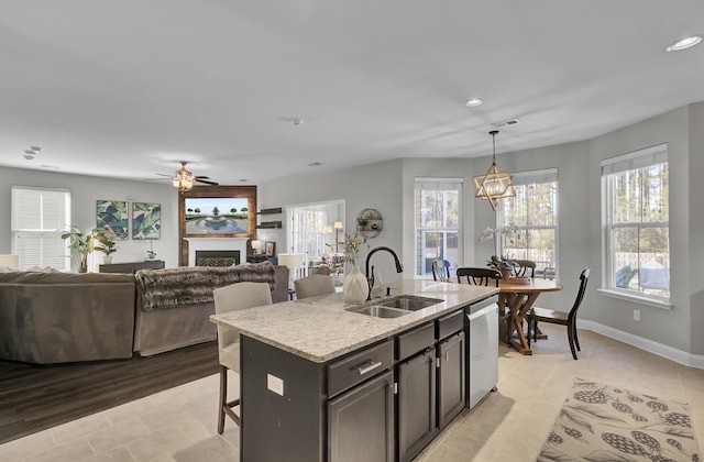 kitchen with pendant lighting, sink, dishwasher, a wealth of natural light, and a center island with sink