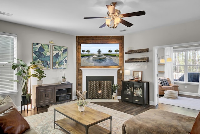 living room with dark wood-type flooring, a fireplace, and ceiling fan