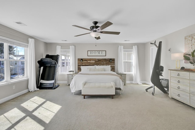 bedroom with multiple windows, light colored carpet, and ceiling fan