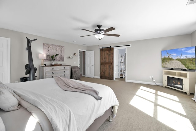 carpeted bedroom with ceiling fan and a barn door