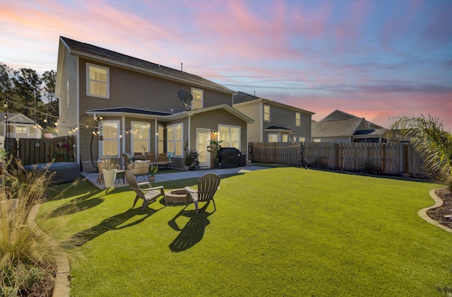 back house at dusk with a yard and a fire pit