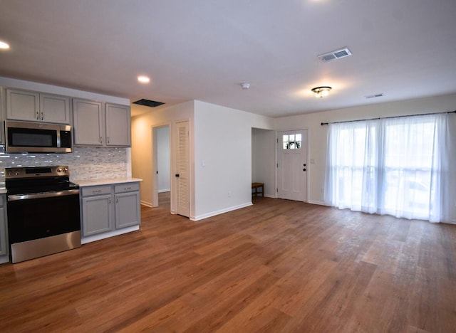 kitchen featuring gray cabinetry, range with electric stovetop, visible vents, light countertops, and stainless steel microwave