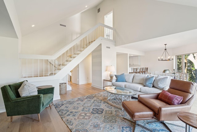 living room featuring high vaulted ceiling, a chandelier, and light wood-type flooring