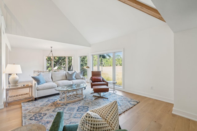 living room featuring beamed ceiling, light wood-type flooring, high vaulted ceiling, and a chandelier